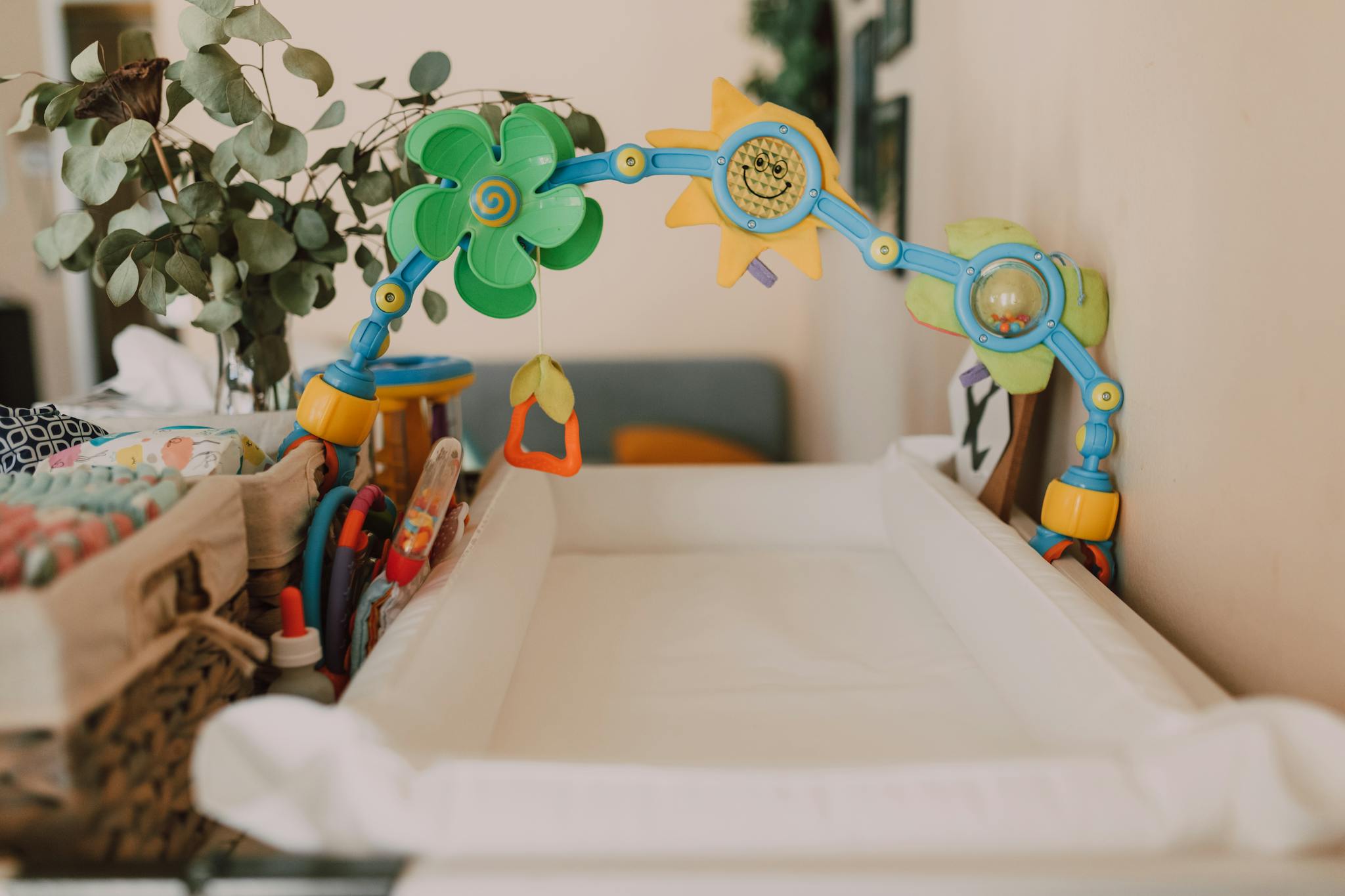 A baby changing table with toys and decor in a cozy nursery, featuring colorful elements and indoor plants.